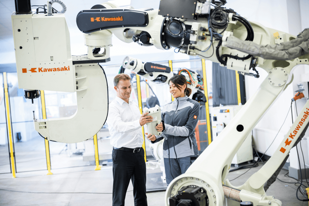homme et femme dans une usine avec bras robotisé