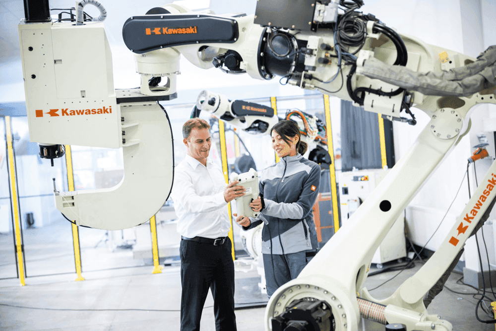 homme et femme dans une usine avec bras robotisé